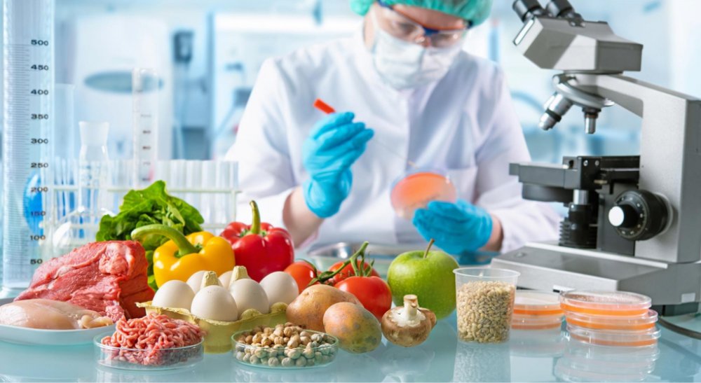Científico en laboratorio analizando alimentos como vegetales, carnes y granos, simbolizando el trabajo en biotecnología alimentaria que realizan startups israelíes para innovar en el sector climático.
